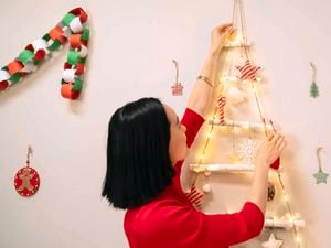 Lady hanging christmas lights on small Christmas tree