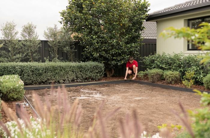 A Bunnings Team Member is measuring the space to install the synthetic turf.