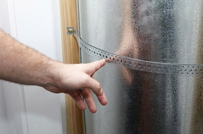 Hot water tank secured against wall.