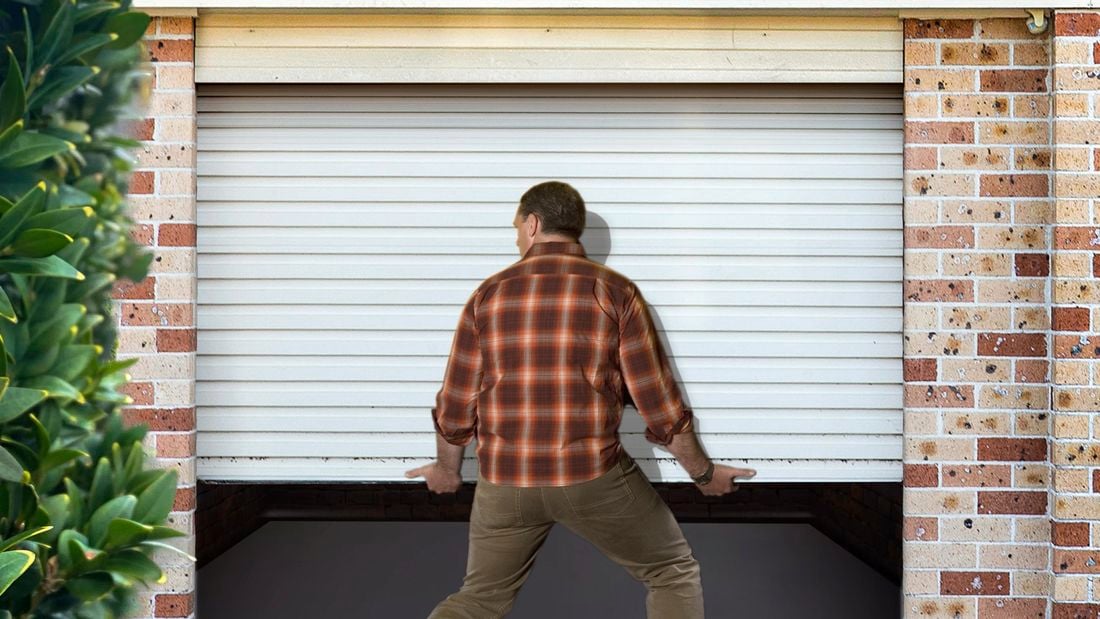 Man lifting up white garage door with bare hands