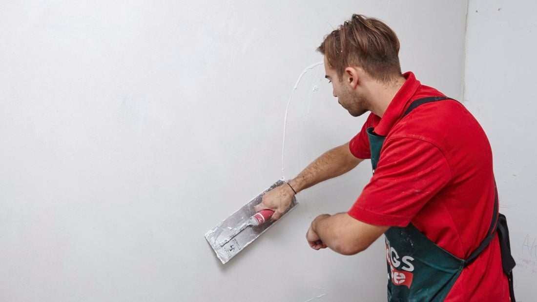 Plaster being applied to an indoor wall by a Bunnings team member with a trowel