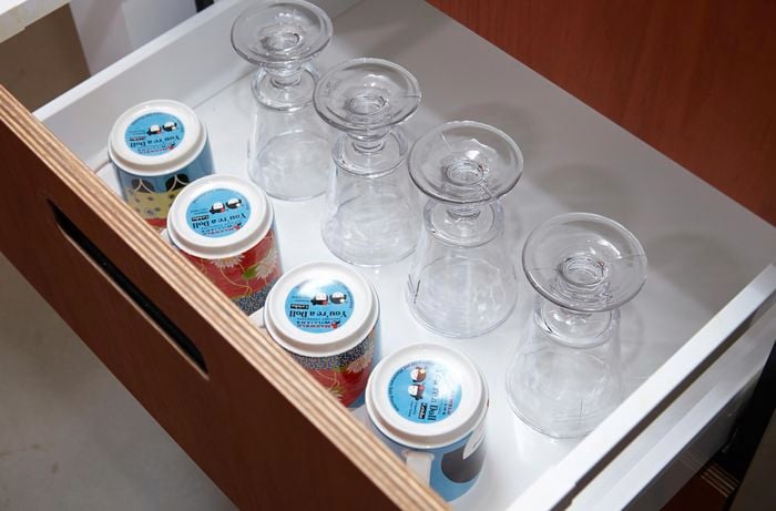 Cups and mugs upside down in an open drawer.