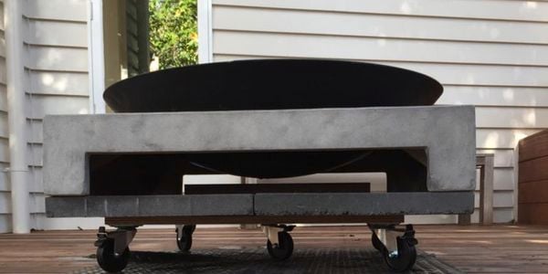 A small fire pit on wheels on a timber deck