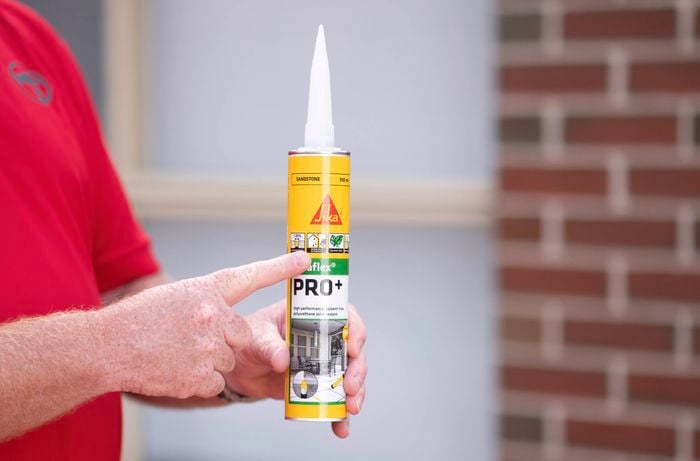 A Bunnings team member is holding a tube of Sika Pro+ Polyurethane Sealant.