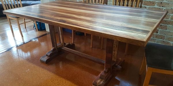 Timber table in a living room surrounded by dining chairs