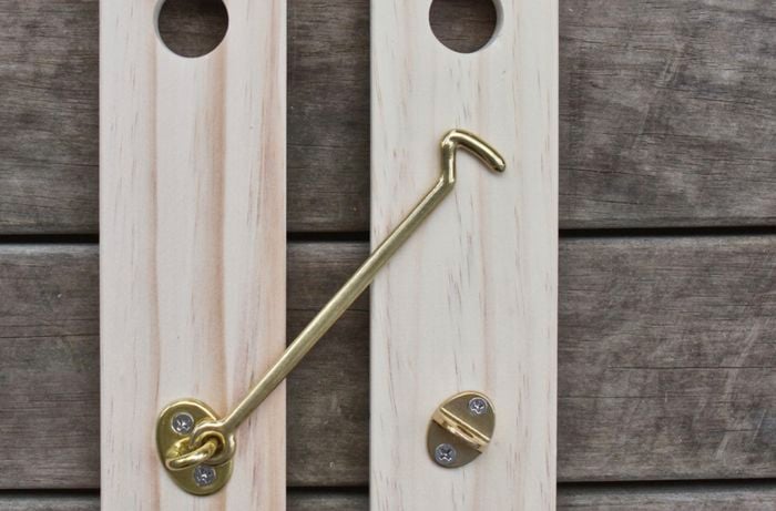 A brass cabin hook secured to two lengths of timber
