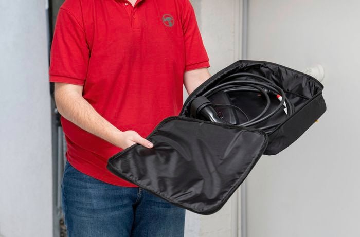 A Bunnings Team Member is holding an open black carrying case containing a Tesla EV charging cable.  