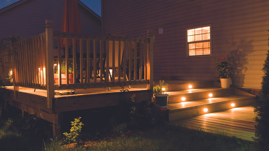 outdoor raised decking area with timber railing and soft lightig