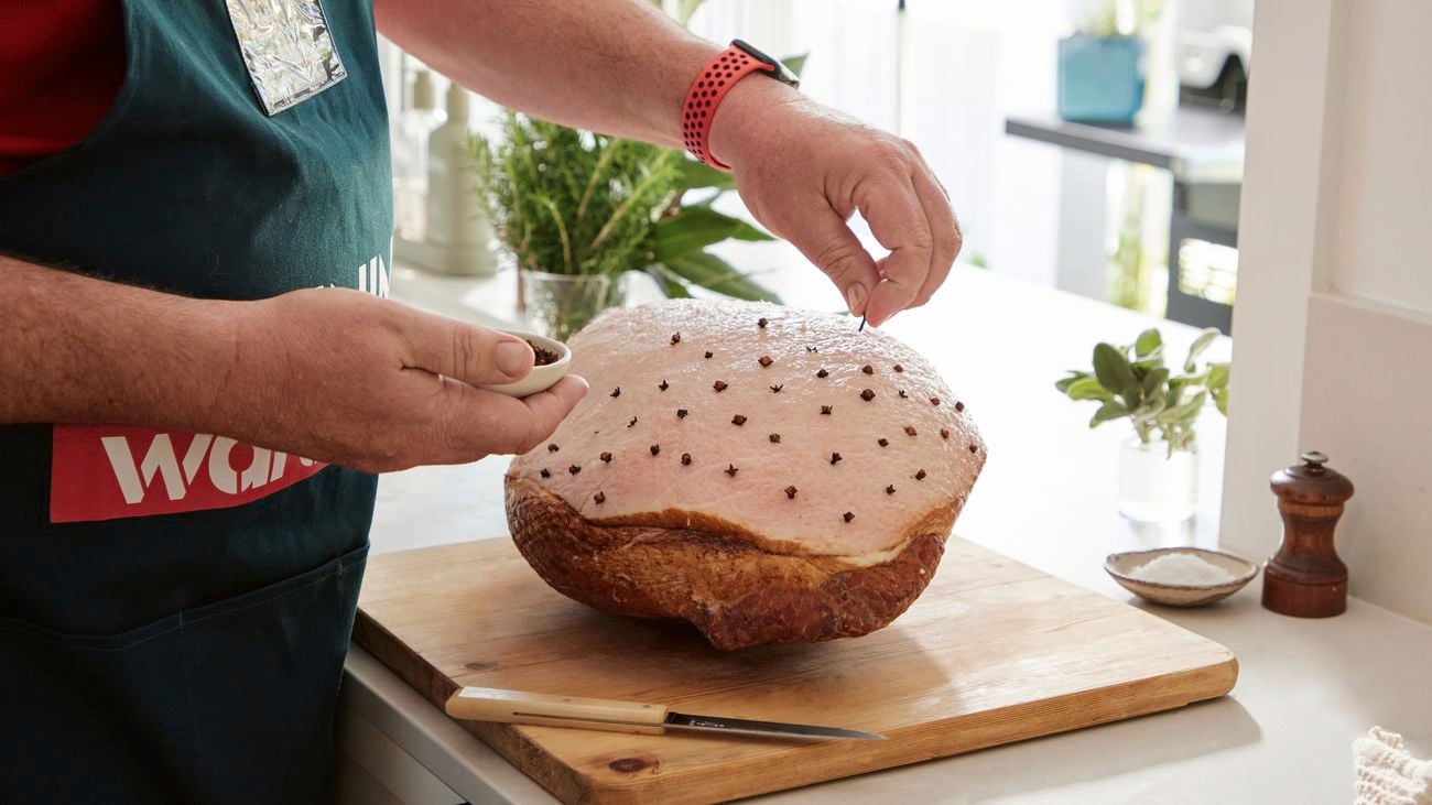 A Bunnings employee pushes garlic cloves into score piece of ham.