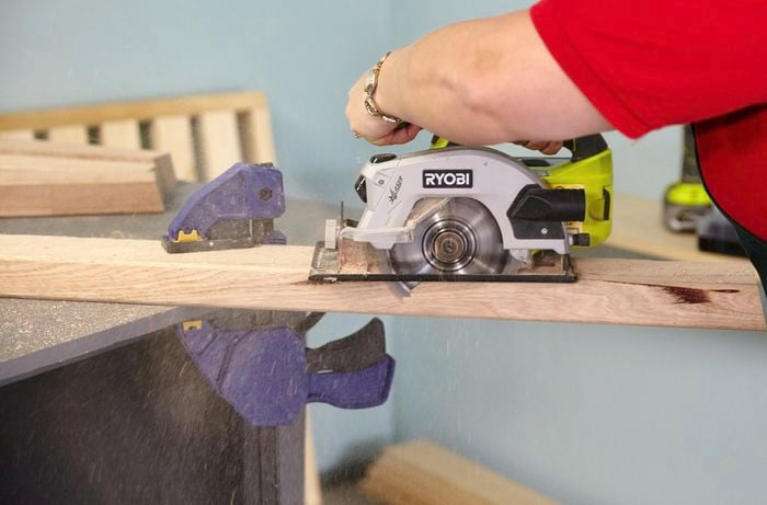 Person cutting timber bed leg with circular saw