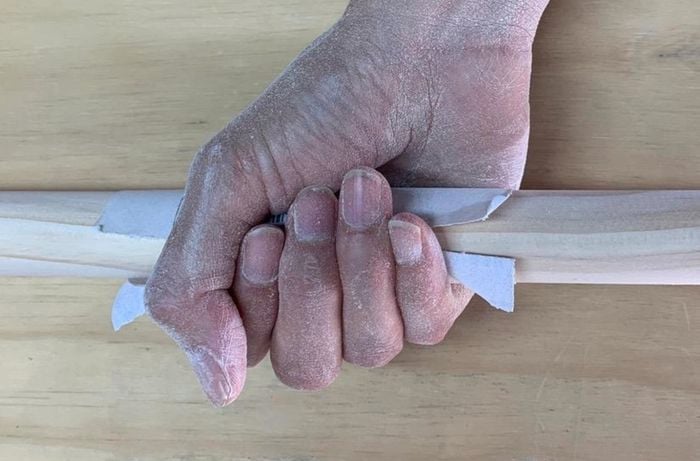 Sanding a length of timber in preparation for varnishing