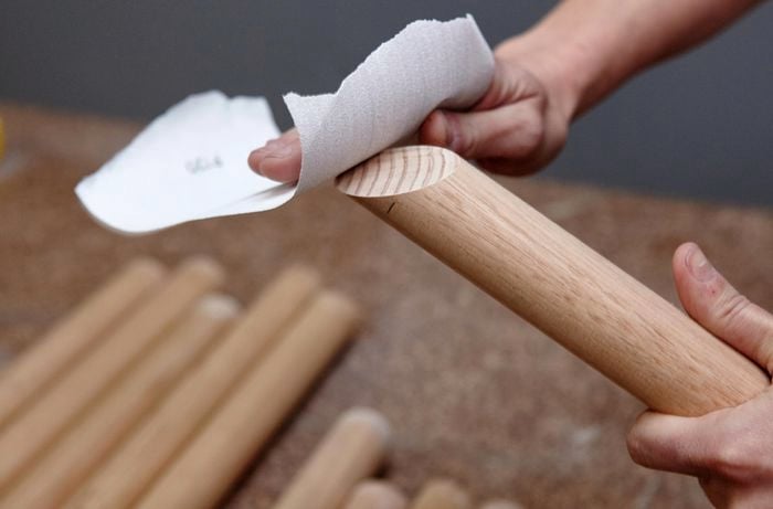 A piece of dowel cut at an angle being sanded