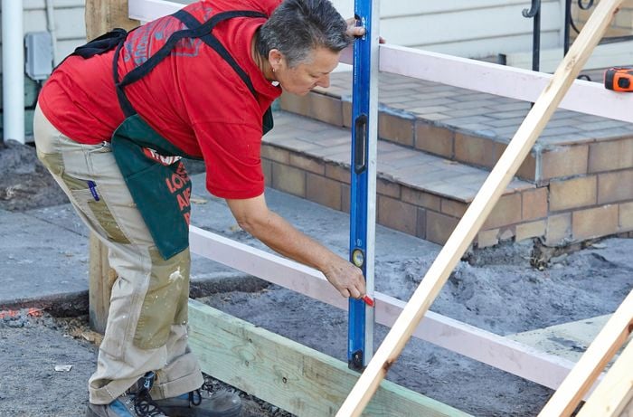 A Bunnings team member using a spirit level to check the angle of an upright fencepost