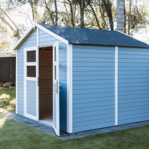 Light blue timber shed with white trim, pitched roof, and glazed double doors standing open to reveal an empty interior.