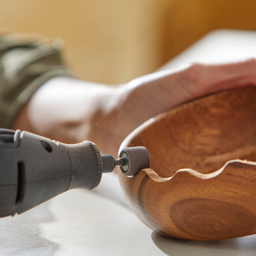 Dremel tool sanding the edge of a wooden bowl.