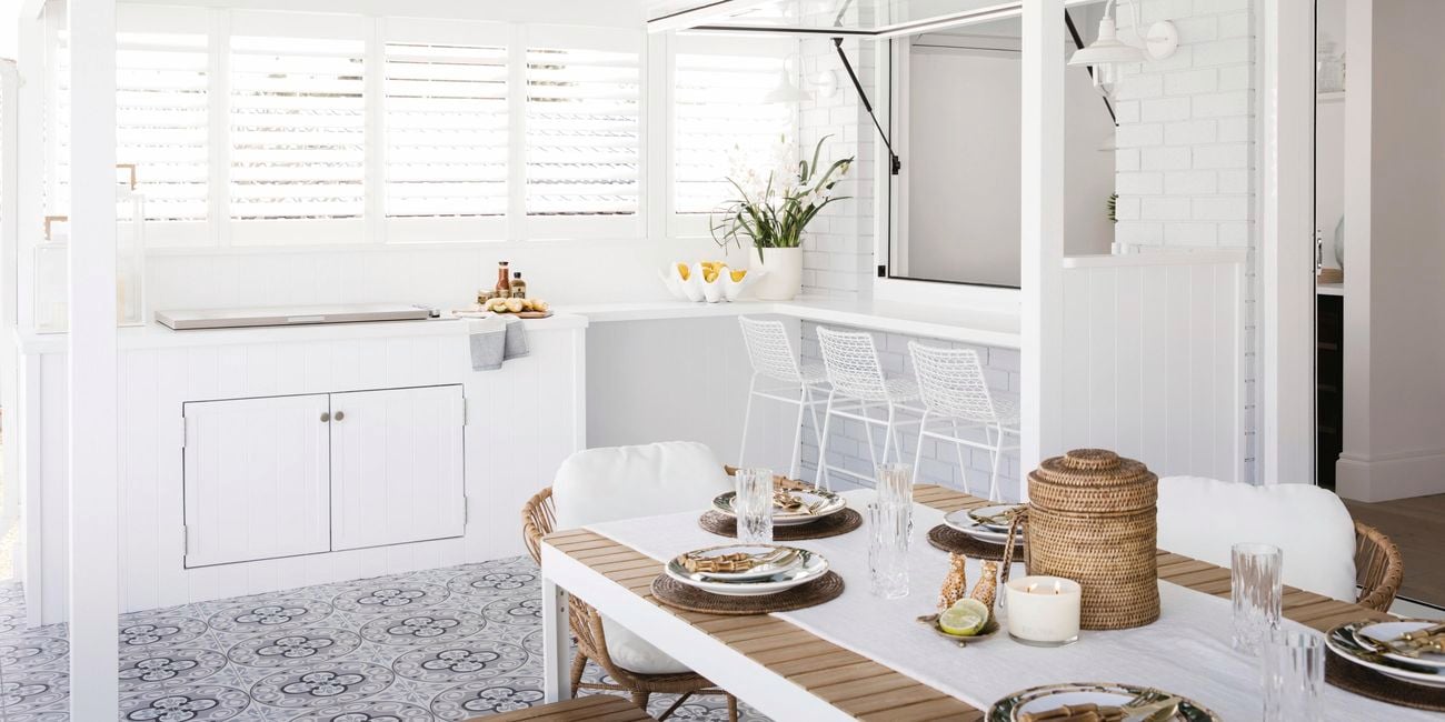 Outdoor kitchen with dining table and white cabinets