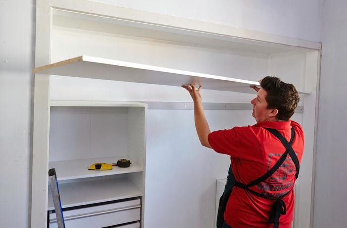 Person placing top shelf on top of wardrobe unit.