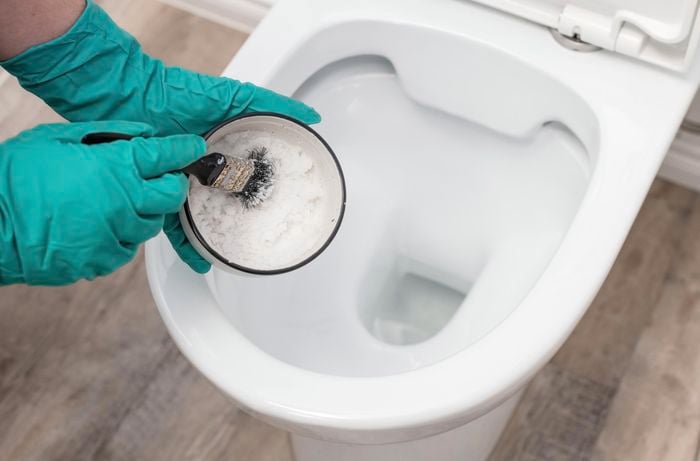 A Borax paste being used to scrub stubborn stains in a white toilet bowl