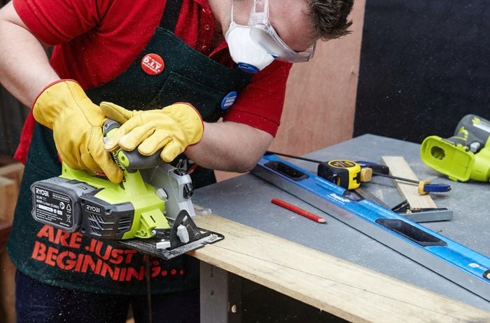 Person using circular saw to cut piece of timber that's clamped to the workbench.