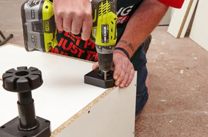 Legs being affixed to an oven cabinet