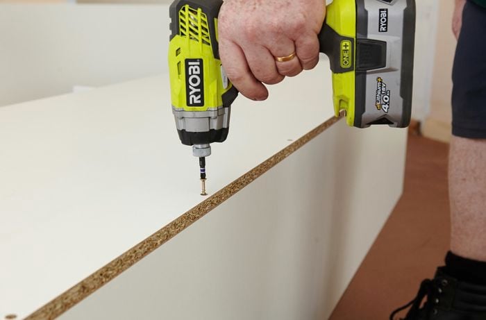 Person drilling screw into panel of pantry
