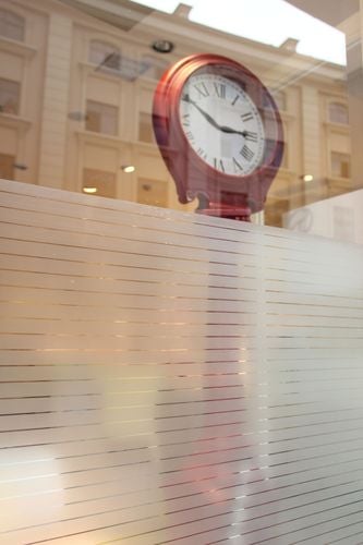 A large timepiece seen through a window made from partially smoked glass