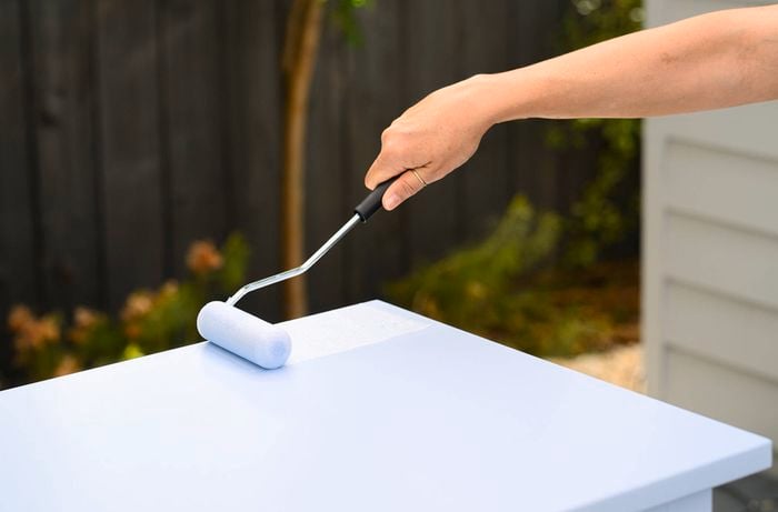 Base colour being rolled onto drawer cabinet using a small paint roller.