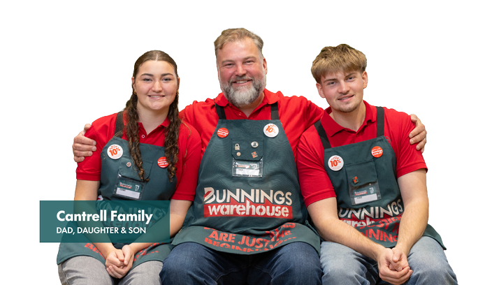 Three Bunnings team members seated together against a light grey background, wearing red polo shirts and dark green Bunnings Warehouse aprons. A teal text panel reads “Cantrell Family, Dad, Daughter & Son.”