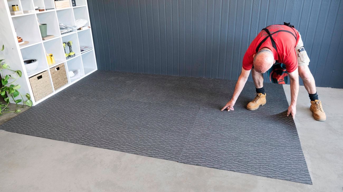 Bunnings team member laying down carpet tiles.