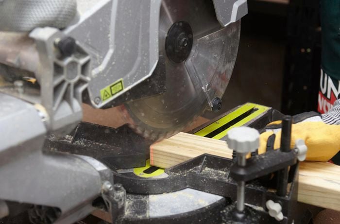 Person using circular saw to cut piece of timber.