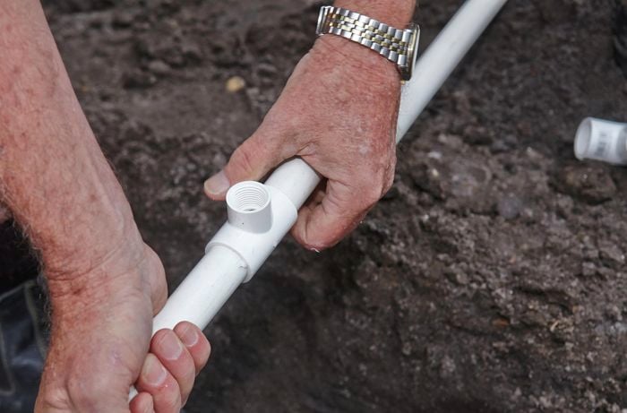 A person joining two lengths of PVC pipe with a T-joint