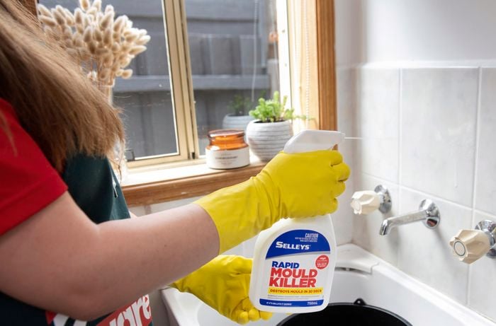 Mould killer being sprayed on a bathroom wall
