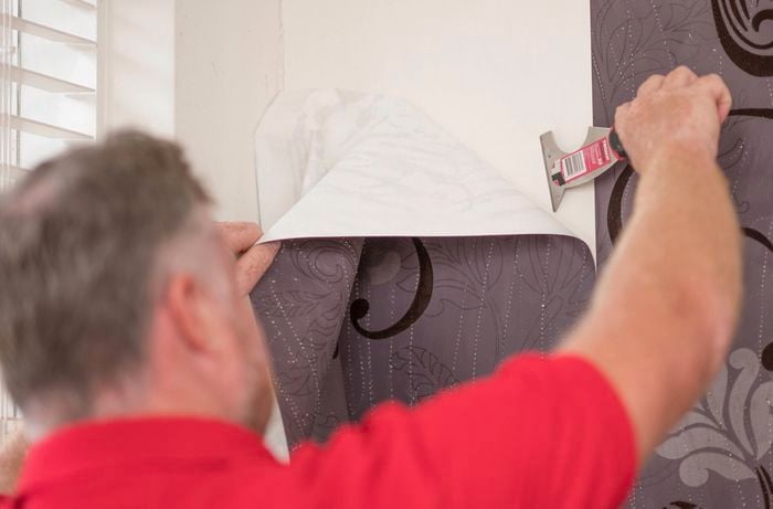 Scraping off the wallpaper with a wallpaper scraper.
