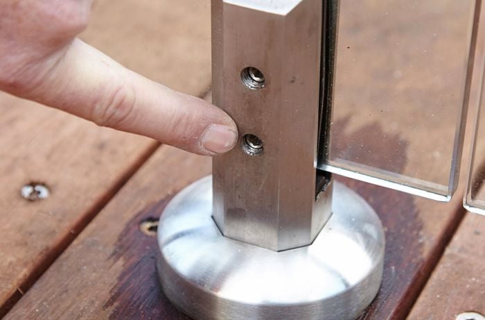 Screw holes in a bracket used to secure the individual panels of a glass pool fence