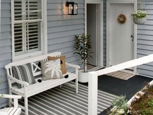 The back of a coastal-style home with freshly painted weatherboard, painted white doors and trims and styled with natural textured rugs