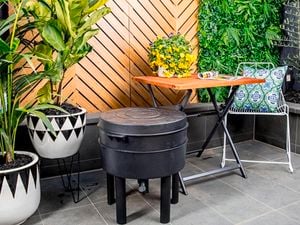 A worm farm in a paved outdoor area with furniture