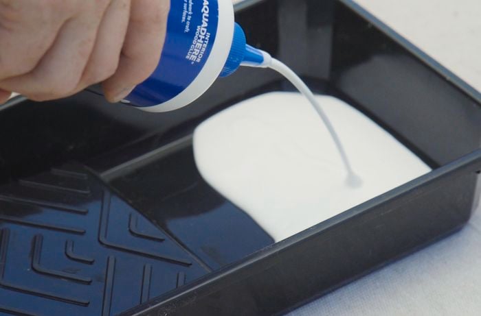 Person pouring wood glue into a paint tray