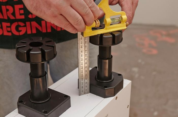 Person adjusting feet to be same length on base of wine rack