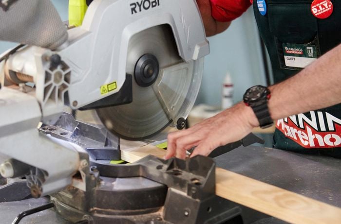 A person cutting timber using a drop saw