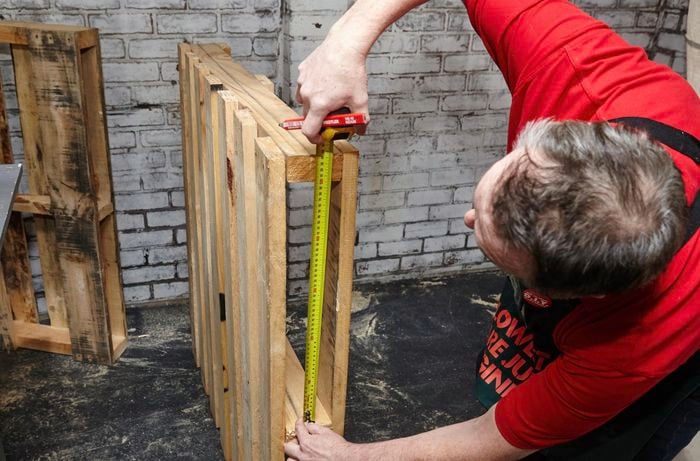 A pencil and tape measure being used to mark a wooden pallet for cutting