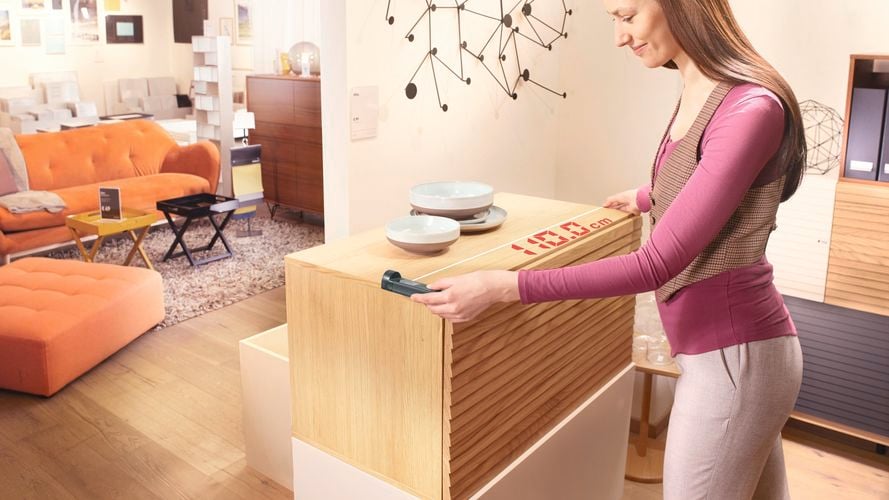 A woman measures a piece of timber furniture in her living room