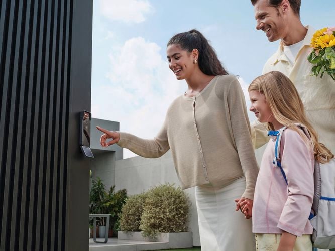 Family standing in front of a door equipped with a Philips Weatherproof Smart Lock.