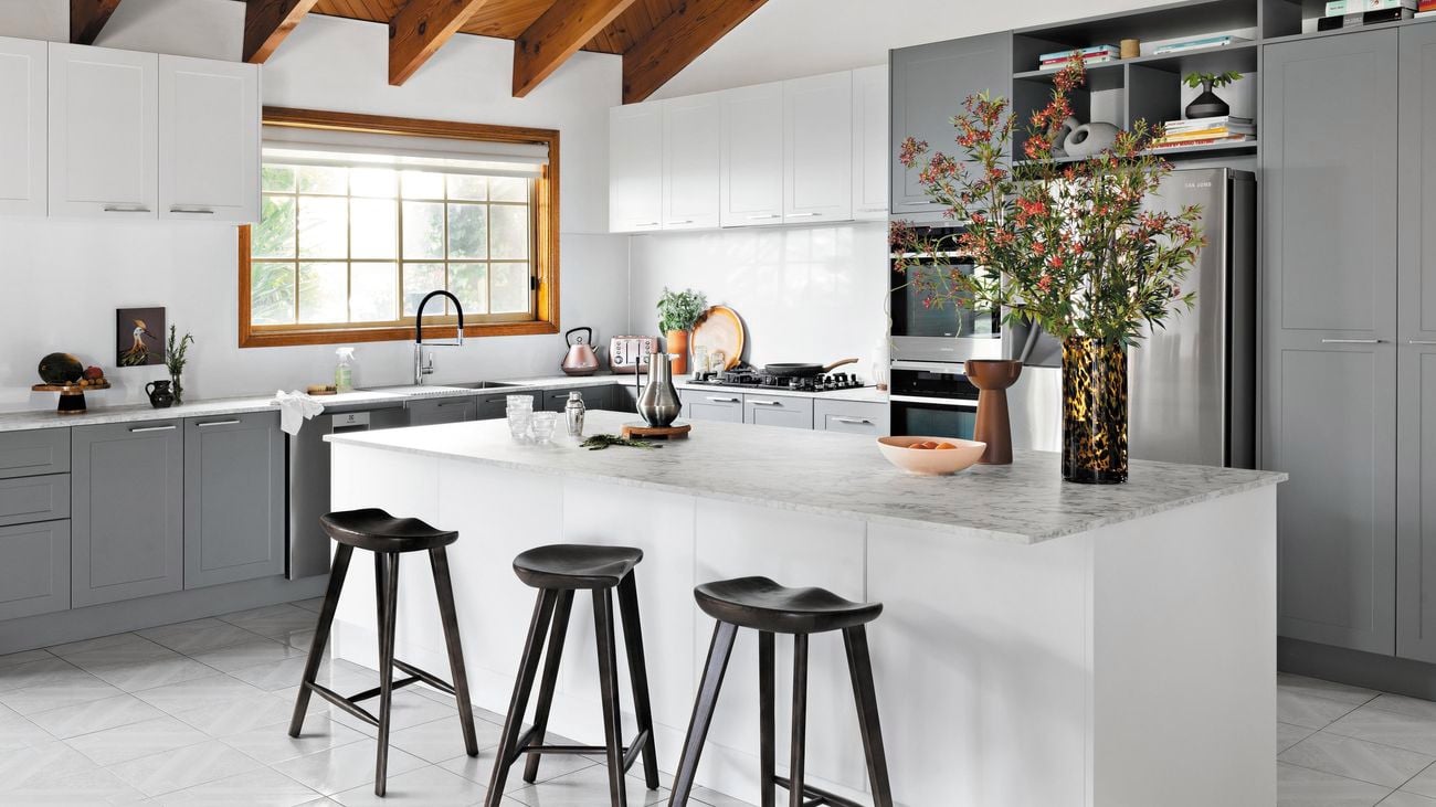 Kitchen with white and grey cabinets, a marble benchtop and a timber ceiling.