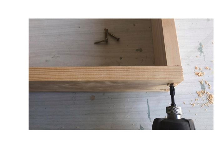 Person drilling two bits of timber together to create frame.
