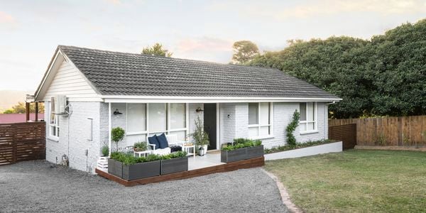 Grey brick house with front patio and lawn.