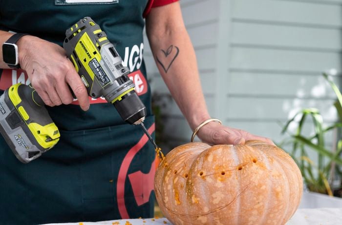 Bunnings team member drilling a pumpkin.