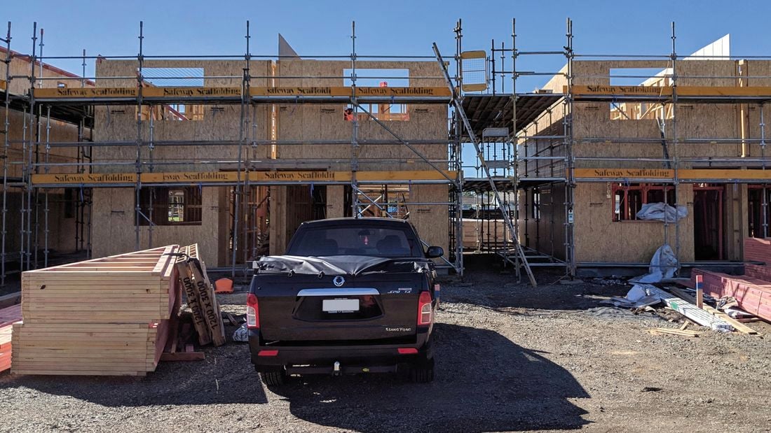 Scaffolding in front of a building under construction, using OSB wall panels