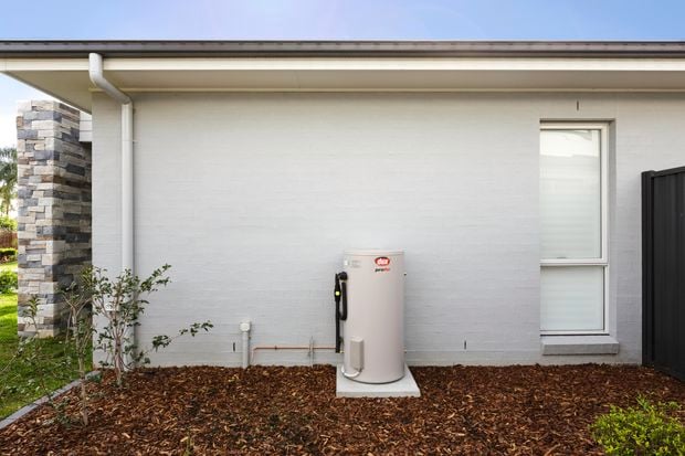 Hot water system located at the back of a rendered brick house