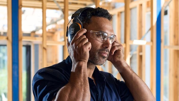                     Person wearing protective earmuffs inside a partially constructed building frame.