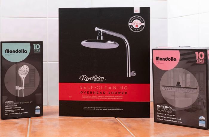 Different shower heads are on the tiled floor.